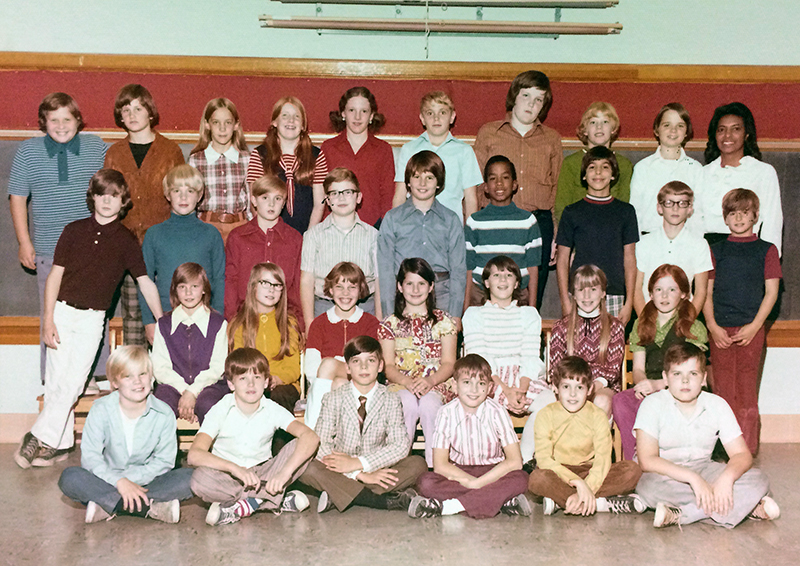 Color class photograph taken during the 1972 to 1973 school year. 31 children and their teacher are posed in a classroom. The children are arranged in four rows in front of a blackboard.