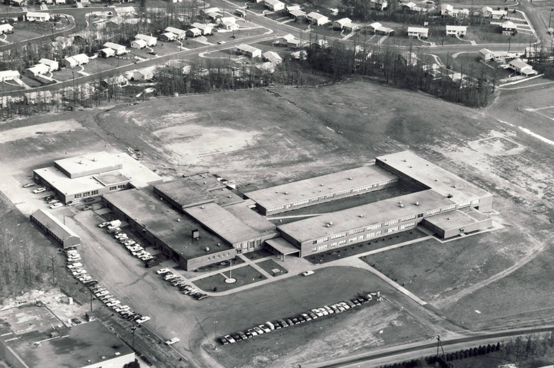Black and white aerial photograph of Washington Irving Intermediate School taken during the 1960s. The L-shaped building is much smaller than it is today. Visible in the distance are the newly built homes along Old Oaks Drive and Greeley Boulevard.